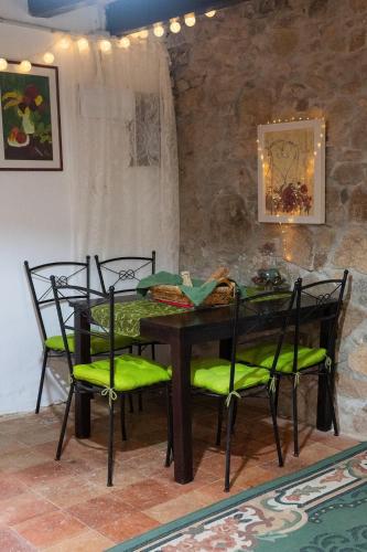 a dining room table with green chairs and a stone wall at Masia Cal Fuster in Joanet