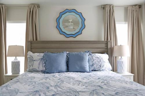 a bed with blue pillows and a picture on the wall at Weekend Away in Dauphin Island