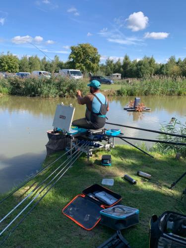 un hombre sentado en una silla frente a un lago en The Purple caravan, en Billinghay