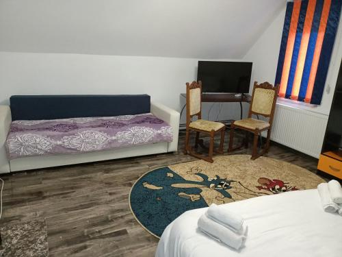 a bedroom with a bed and two chairs and a desk at Casa Maria in Topliţa