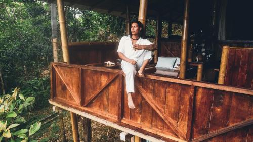 a man sitting on a wooden structure with a laptop at Toucan Lodge in Puyo