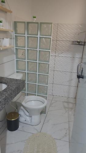 a white bathroom with a toilet and a sink at kitnet in Rio Verde