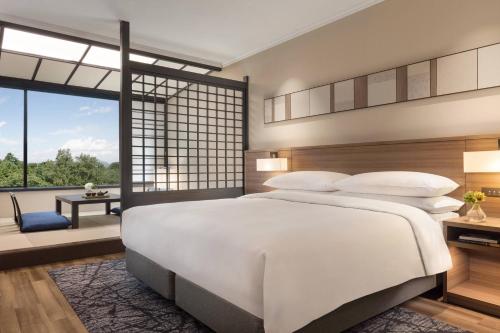 a bedroom with a large white bed and a large window at Izu Marriott Hotel Shuzenji in Izu