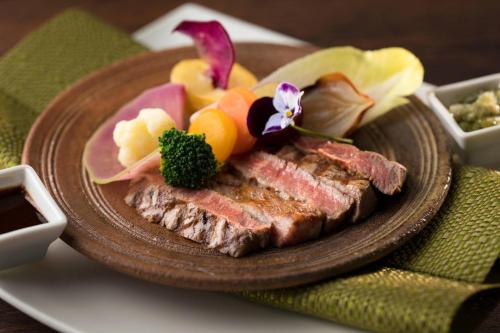 a plate of meat with fruit and vegetables on it at Izu Marriott Hotel Shuzenji in Izu