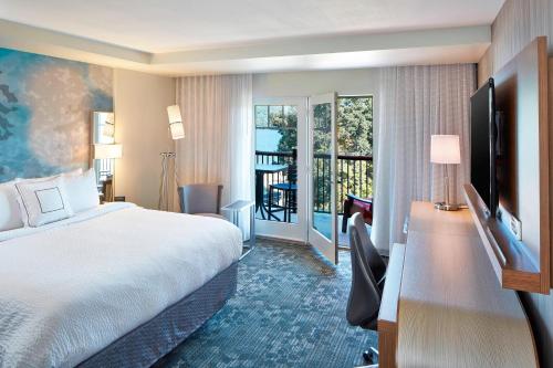 a hotel room with a bed and a balcony at Courtyard by Marriott Lake George in Lake George