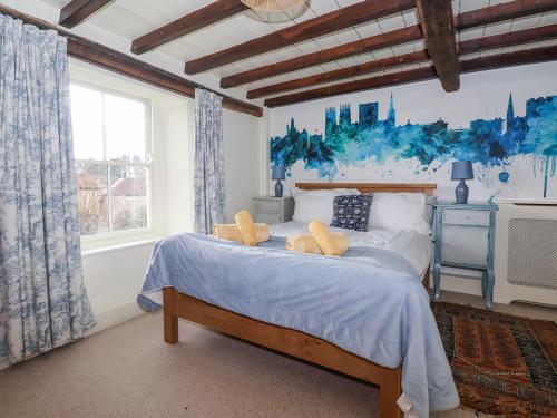 a bedroom with a large bed with a blue painting on the wall at The Old Post Office in Ampleforth