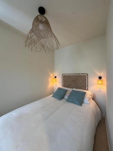- une chambre avec un grand lit blanc et 2 oreillers bleus dans l'établissement Le Bleu de Giens, à Hyères