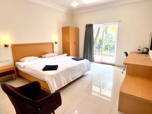a bedroom with a bed with a chair and a window at Morjim Sunset Guesthouse- Apartments with Kitchen & AC Rooms in Morjim
