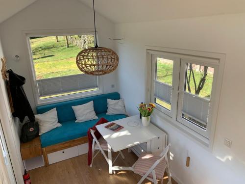 Gemütliches Tiny House in der Rhön في Hilders: غرفة معيشة مع أريكة زرقاء ونافذتين