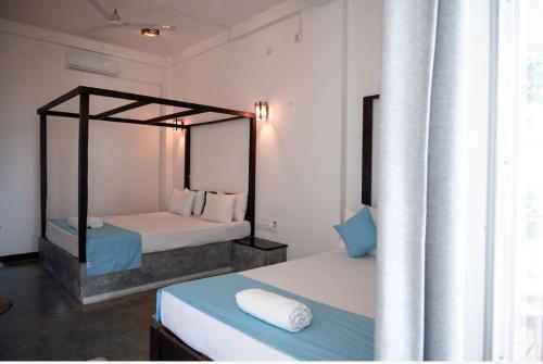 a bedroom with two beds and a canopy bed at Cocos in Midigama