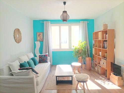 - un salon avec un canapé blanc et un mur bleu dans l'établissement Agréable T2 à 5 min du Palais des Papes avec Wifi Terrasse partagée, à Avignon