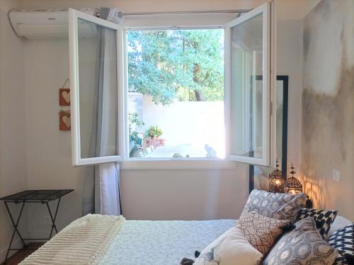 une chambre avec un lit et une grande fenêtre dans l'établissement Agréable T2 à 5 min du Palais des Papes avec Wifi Terrasse partagée, à Avignon