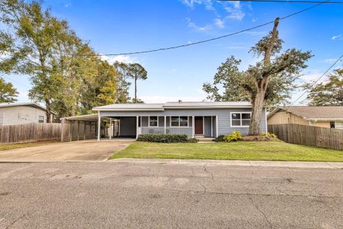 a white house with a fence and a tree at Gulf Breezes in Gulfport