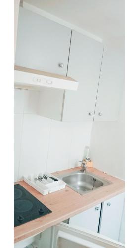 une cuisine avec des armoires blanches et un évier dans l'établissement Car17 -1G, à Paris