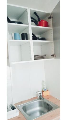 - un évier dans une armoire blanche avec de la vaisselle dans l'établissement Car17 -1G, à Paris