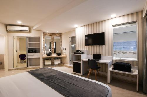 a bedroom with a bed and a desk and a television at Hotel Innovo in Rosario