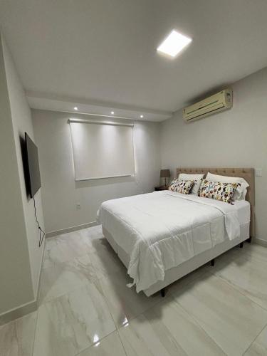 a bedroom with a white bed and a projection screen at Novo e Moderno Apartamento in Boa Vista