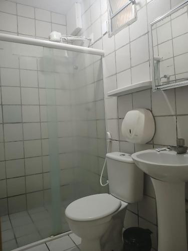 a white bathroom with a toilet and a sink at Pousada Aconchego do Porto in Porto De Galinhas