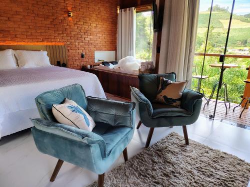 a bedroom with two chairs and a bed and a window at Domus Fiorese Chalés in Venda Nova do Imigrante
