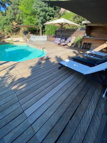 une terrasse en bois avec une piscine et un parasol dans l'établissement Mont Milan, à Peyriac-de-Mer