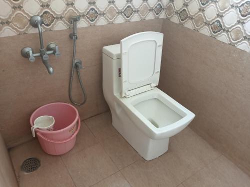 a bathroom with a toilet and a pink bucket at Golden Rooms banglore in Bengaluru