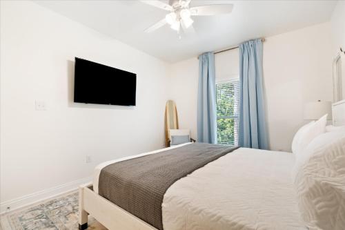 a white bedroom with a bed and a flat screen tv at Brand New Luxury Rental on Oleander Unit E in Dauphin Island