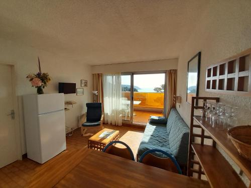 Il comprend un salon doté d'un canapé et une cuisine équipée d'un réfrigérateur. dans l'établissement appartement côte d'azur vue mer, à Roquebrune-Cap-Martin