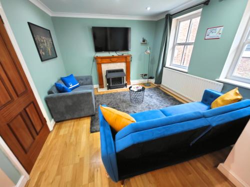a living room with a blue couch and a tv at Charming 3 Bed Home in Central London, Abbey Road in London