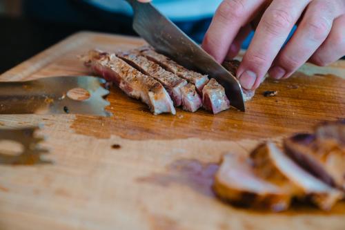 a person cutting up meat on a cutting board with a knife at hoevehotel ter haeghe in Gistel