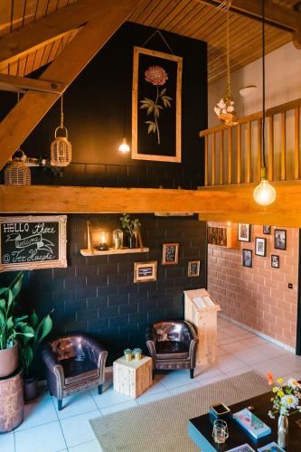 a living room with leather chairs and a brick wall at hoevehotel ter haeghe in Gistel