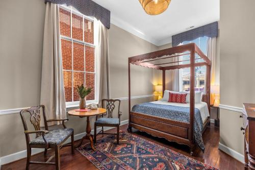 a bedroom with a canopy bed and a table and chairs at Leesburg Colonial Inn in Leesburg