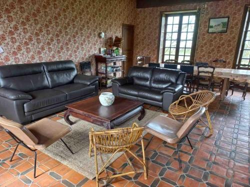 a living room with black leather furniture and a table at Grande maison aux portes de Vire in Burcy