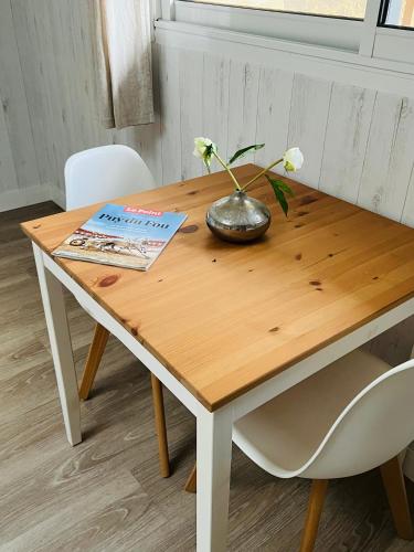 une table en bois avec un vase de fleurs dessus dans l'établissement La grange, aux Herbiers