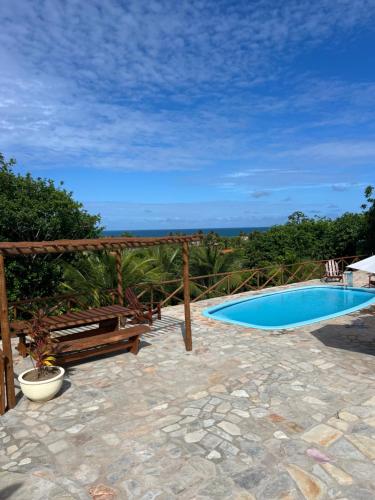 a swimming pool on a patio with a view of the ocean at Pipa Golfinhos Pousada in Pipa