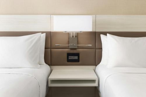 two beds with white pillows and a table between them at AC Hotel St Petersburg Downtown in St Petersburg