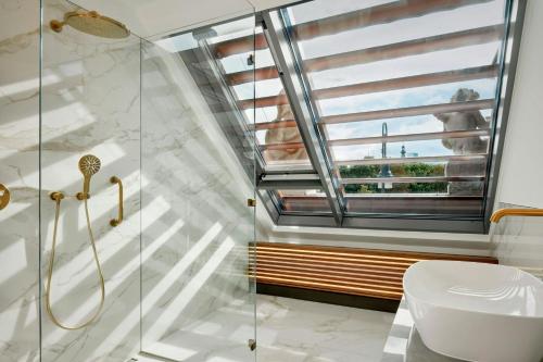 a bathroom with a shower and a toilet and a window at Hotel Verte, Warsaw, Autograph Collection in Warsaw