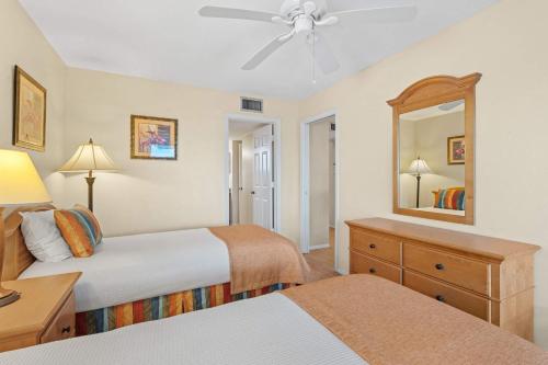a bedroom with two beds and a dresser and a mirror at Scenic Resort Views From This 3rd Floor Deluxe Condo in Naples