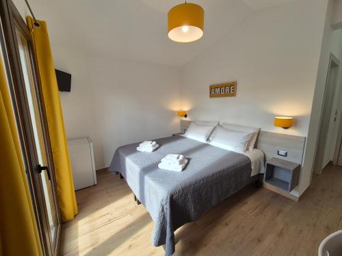 a bedroom with a bed with two towels on it at COMIDA Guesthouse & Experiences in Tortolì