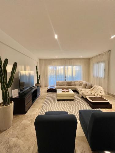 a large living room with a couch and a tv at Departamento exclusivo con playa privada - La Amada, Cancun in Cancún