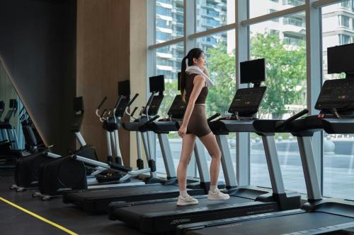 a woman walking on a treadmill in a gym at AC Hotel by Marriott Chengdu North in Chengdu