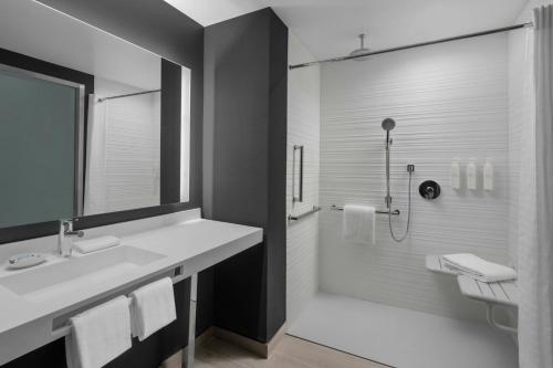 a bathroom with a white sink and a shower at AC Hotel by Marriott St. Louis Clayton in Clayton