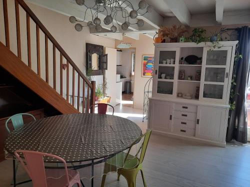 une salle à manger avec une table, des chaises et une armoire dans l'établissement Maison Gruissan village 90m2 avec jardin a 1km de la plage, à Gruissan