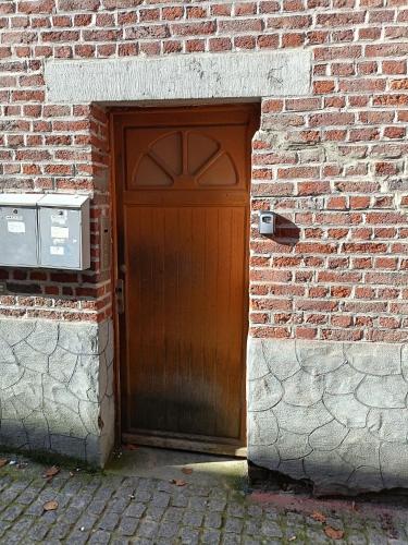 a wooden door in a brick building with a brick wall at Maison du Doudou centre ville in Mons