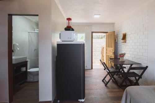 a kitchen with a microwave on top of a refrigerator at Pousada Hanalie by Easy Hotéis in Praia do Rosa