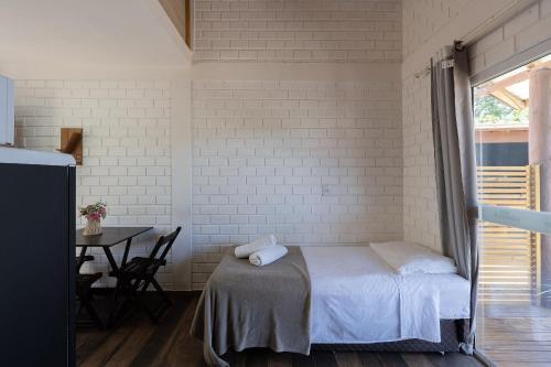 a white room with a bed and a table with a tableablish at Pousada Hanalie by Easy Hotéis in Praia do Rosa