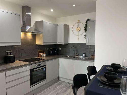 a kitchen with white cabinets and a stove top oven at Wild Central Suite - Ping Pong Table, Free Gym in Leicester