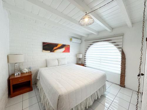 a white bedroom with a bed and a window at Castillos Del Mar in Rosarito