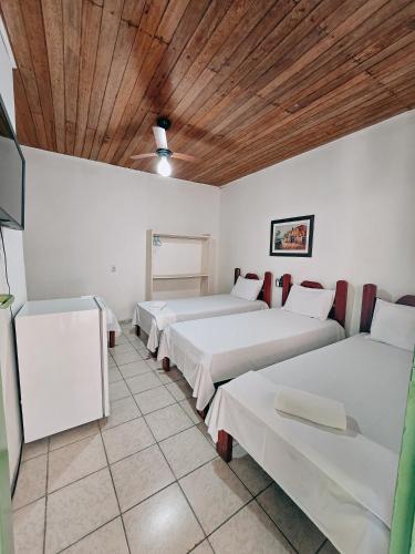 a room with three beds and a wooden ceiling at Pousada Rio do Prado in Porto Seguro