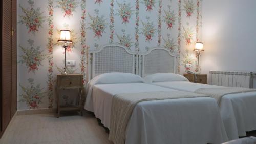 two beds in a bedroom with floral wallpaper at Hotel Rural Eloy in Baños de Montemayor