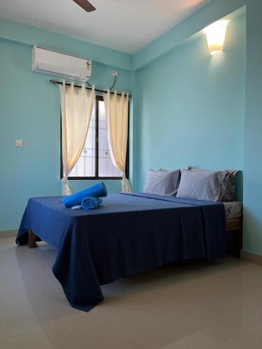 Un dormitorio azul con una cama y una ventana. en Paris Apartment, en Pondicherry